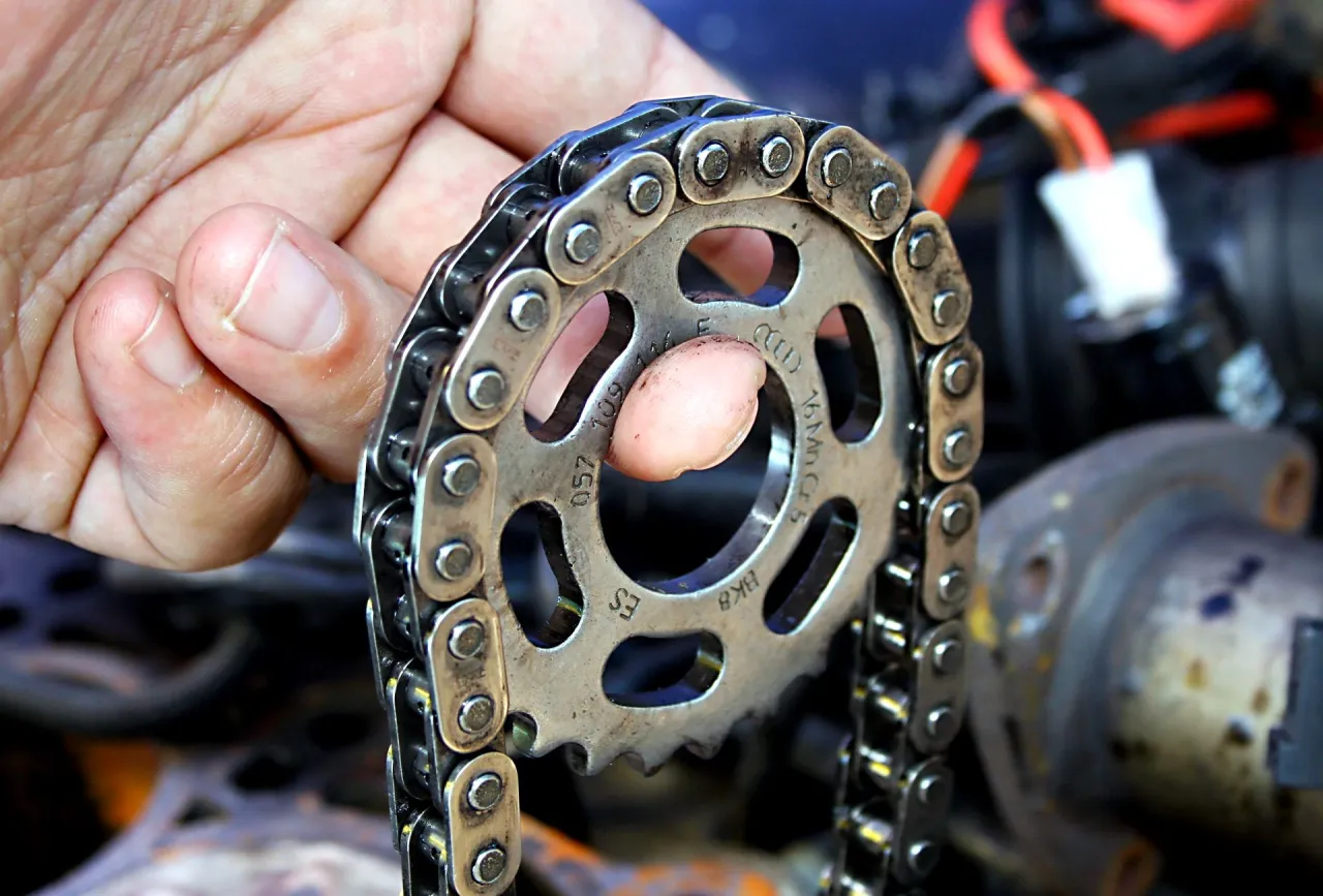 Dłoń trzyma koło zębate i łańcuch, element kluczowy dla prawidłowego działania rozrządu w aucie.