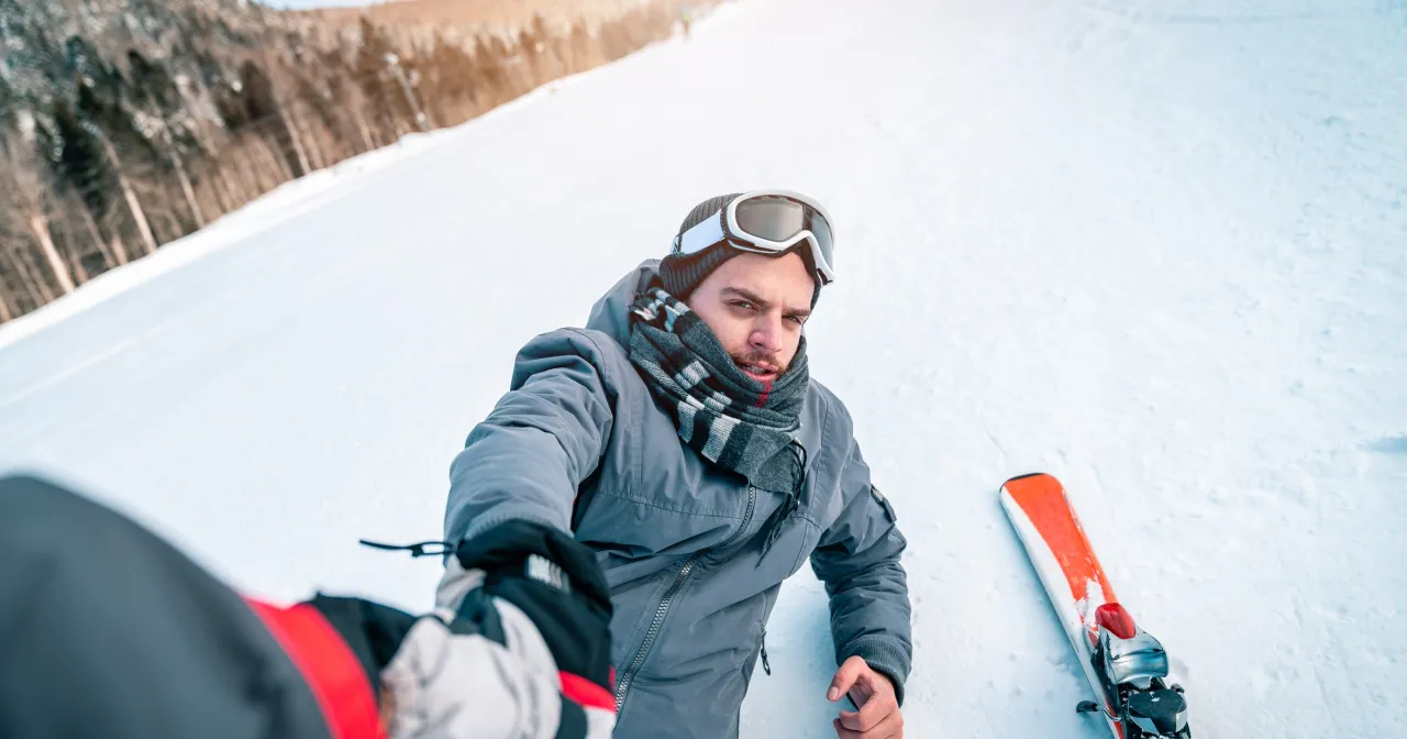 Mężczyzna na stoku narciarskim we Włoszech, z nartami obok. Pamiętaj o ubezpieczeniu narciarskim Włochy!