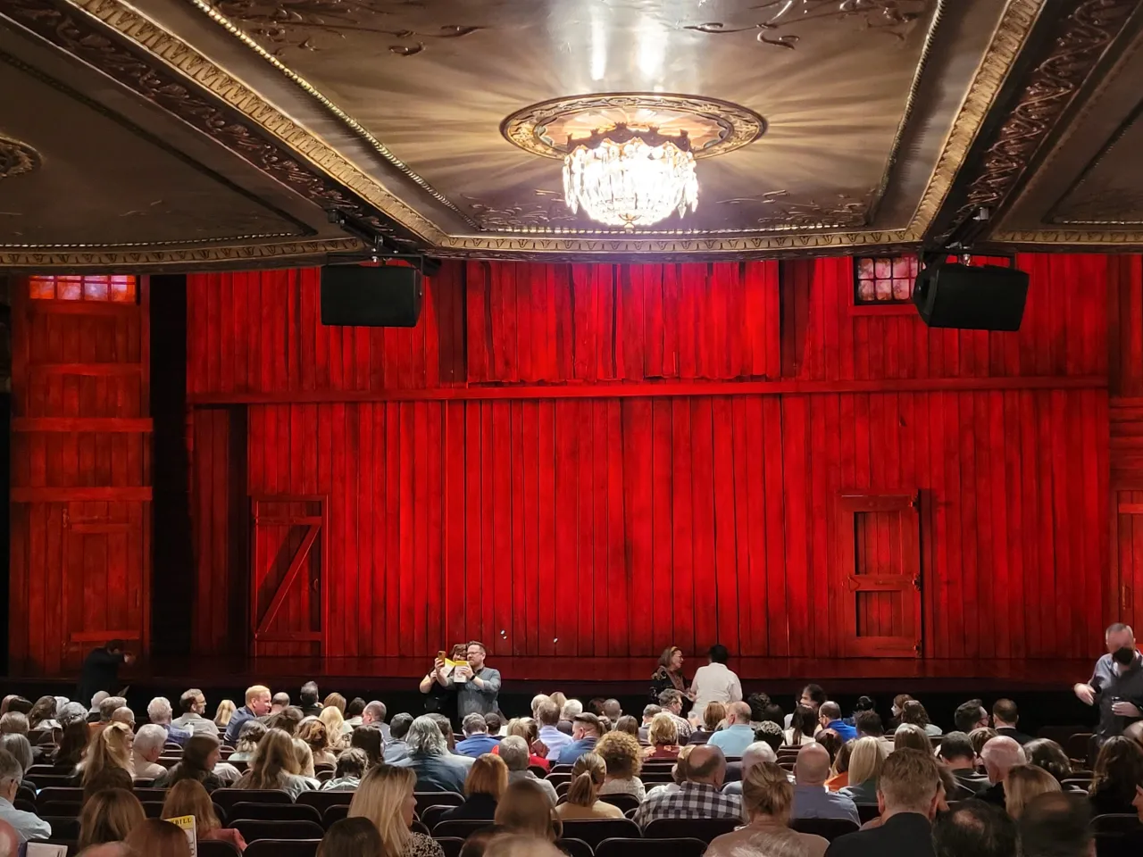 Widownia teatru z czerwonymi zasłonami. Zastanawiasz się, ile kosztują bilety do teatru?