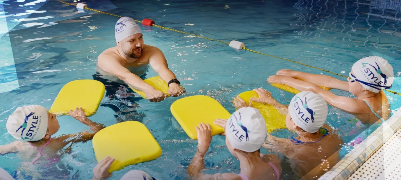 Instruktor pokazuje dzieciom, jak nauczyć się pływać w starszym wieku, używając desek do pływania.