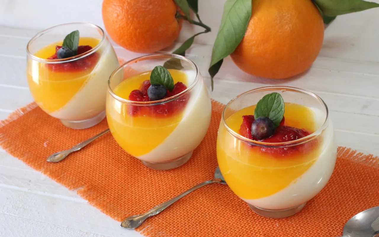panna cotta de naranja con salsa de frutos rojos en una copa de cristal