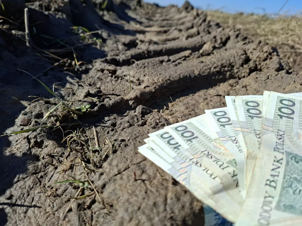 Pieniądze leżą na błotnistej drodze, sugerując, kto dostanie dofinansowanie do węgla.