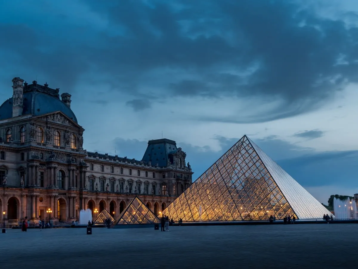 Wieczorem Luwr z lśniącą piramidą. Zwiedzanie tego miejsca to przygoda na wiele godzin, zastanawiasz się, ile czasu zwiedza się Luwr?