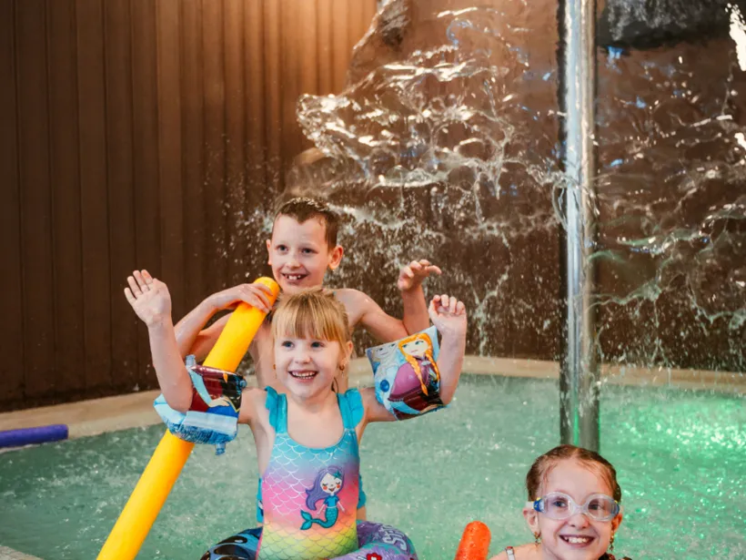 dzieci bawiące się w basenie hotelowym pod opieką rodziców