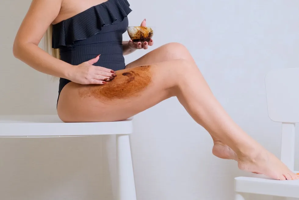 kobieta nakładająca peeling kawowy na uda