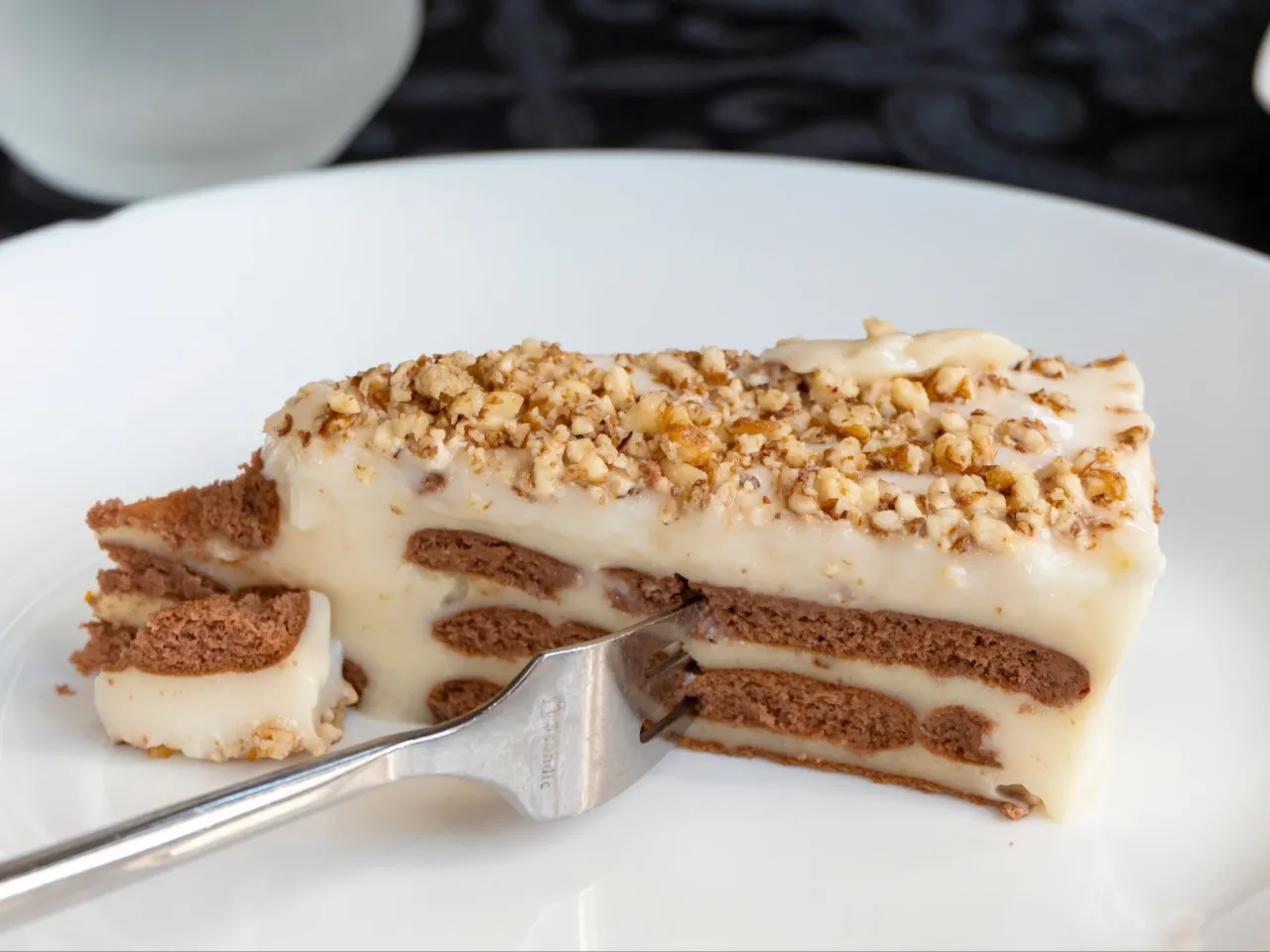 Pyszny deser z herbatnik&oacute;w i kremu budyniowego, posypany orzechami. Idealny pomysł na to, co można zrobić z ugotowanego budyniu.