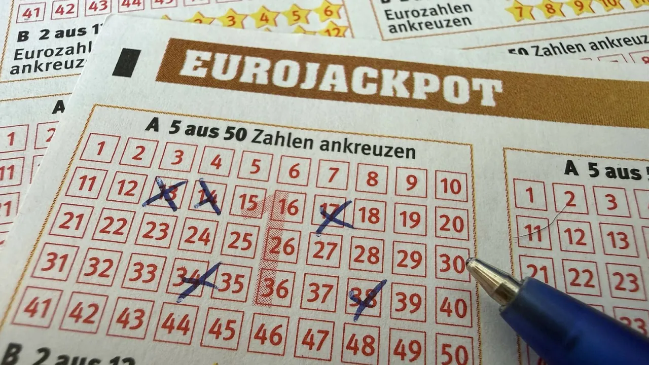 Kupon Eurojackpot z zaznaczonymi liczbami. Czy wygraną w eurojackpot można odebrać w innym kraju? Pytanie wisi w powietrzu, gdy długopis czeka na kolejne liczby.