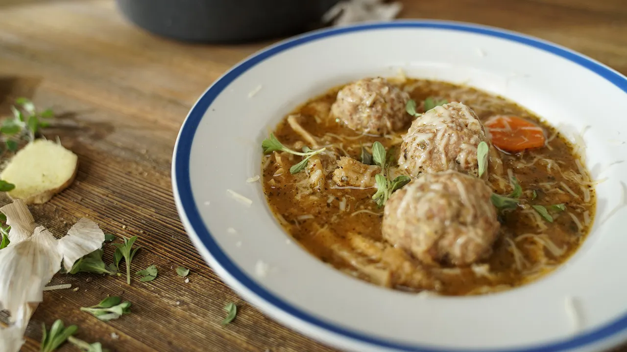 Talerz flaków z kluskami, posypany serem i ziołami. Obok czosnek i imbir, które dodajemy do flaków.