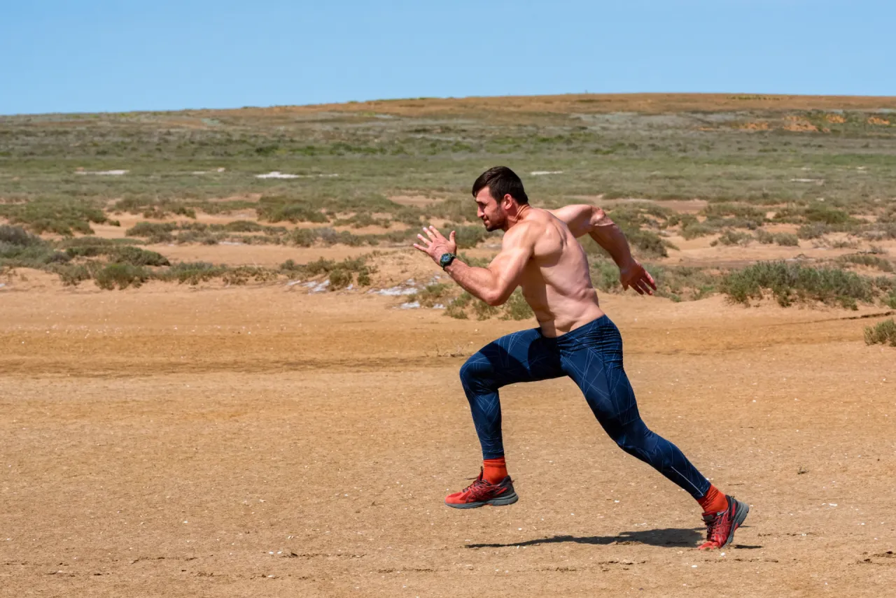 Osoba biegnąca w miejscu w domu, z widocznymi mięśniami n&oacute;g i sylwetką