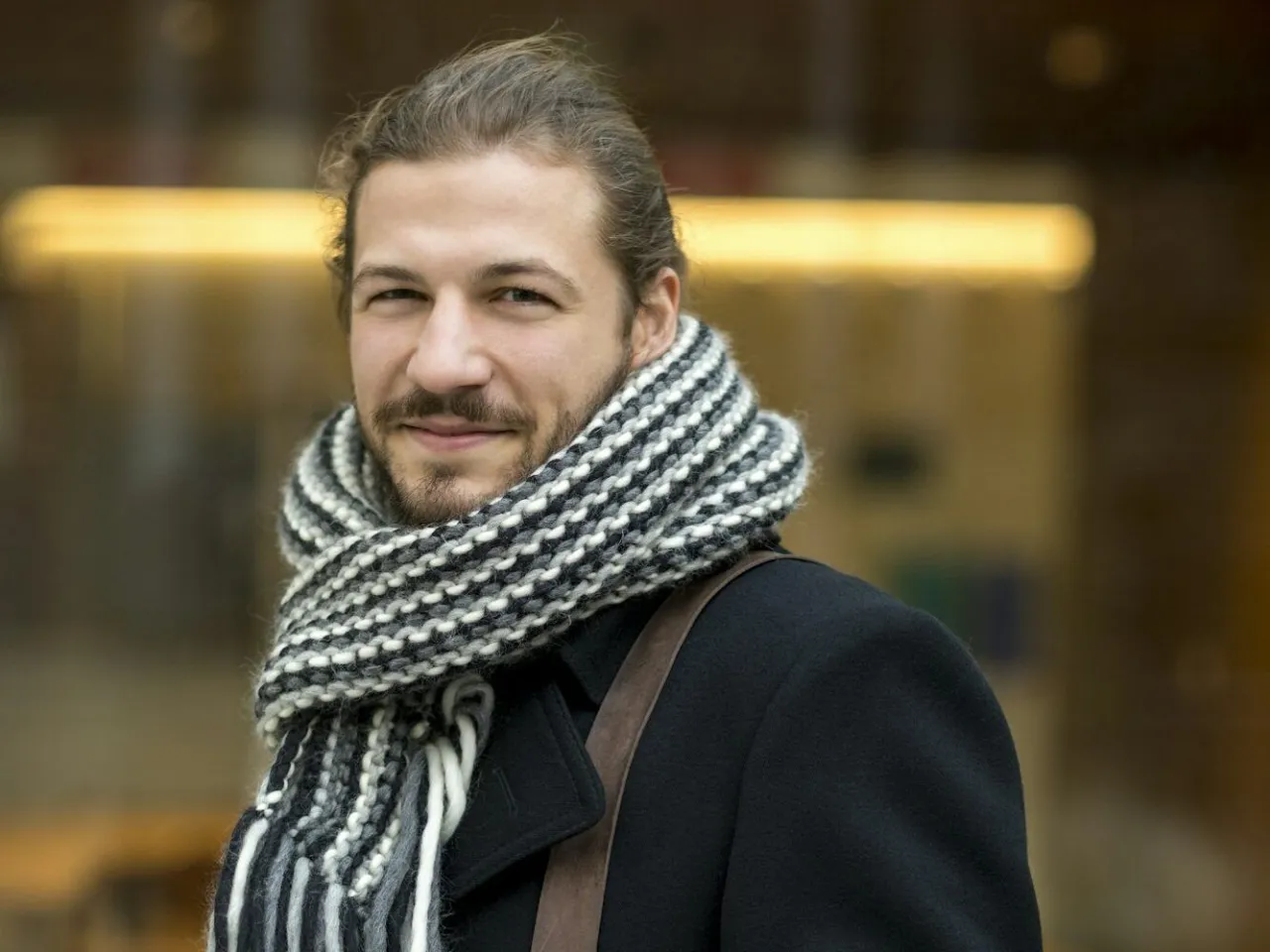 mężczyzna w eleganckim płaszczu z modnie zawiązanym szalikiem