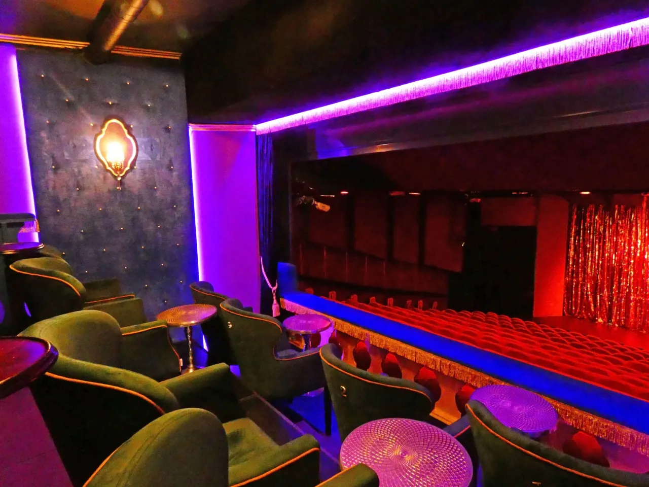 Luksusowe fotele i scena w Capitol Club Warszawa, oświetlone fioletowym blaskiem.