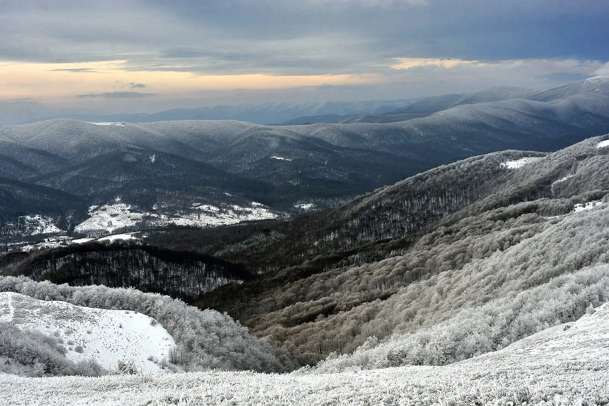 Zimowe szlaki w Bieszczadach otwarte, pokryte śniegiem i szadzią. W oddali widać kolejne pasma górskie.