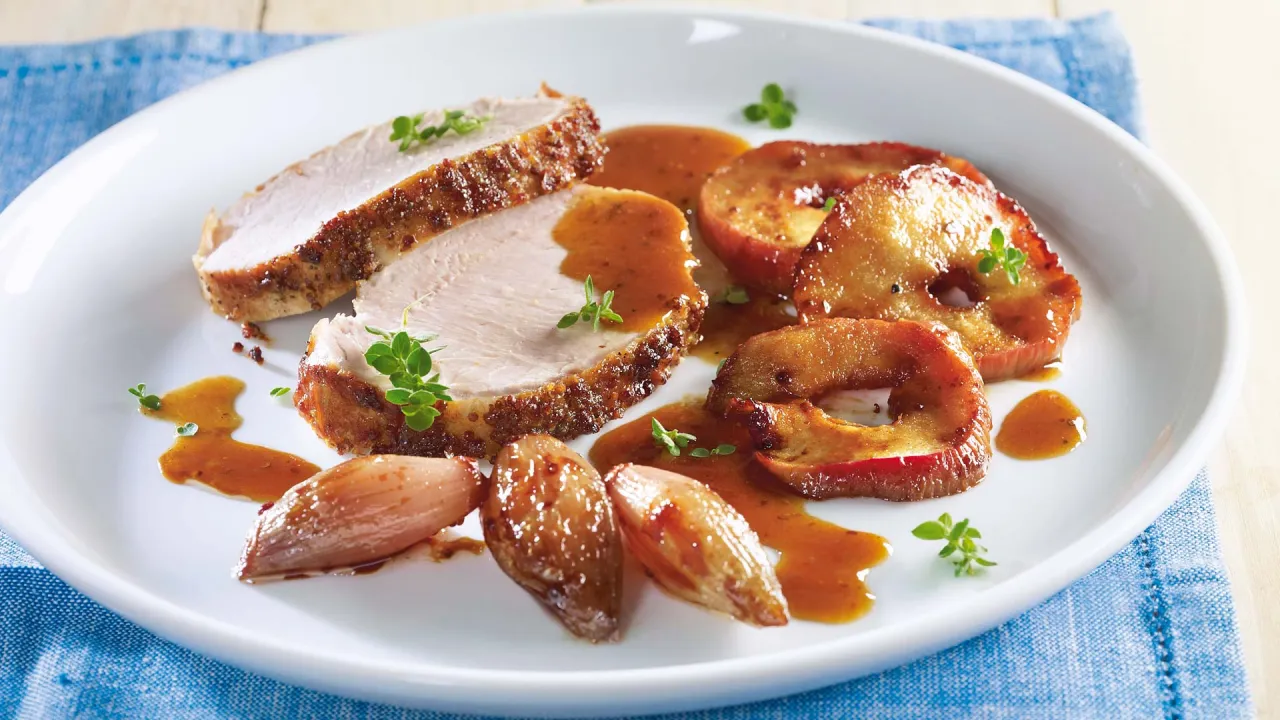 Schweinebraten mit Apfelfüllung und knuspriger Kruste auf einem Teller