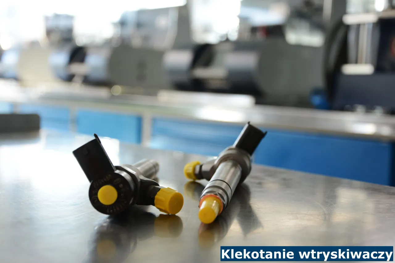 Dwa wtryskiwacze do silnika diesla leżące na metalowym blacie. Mogą być przyczyną cykania w silniku.