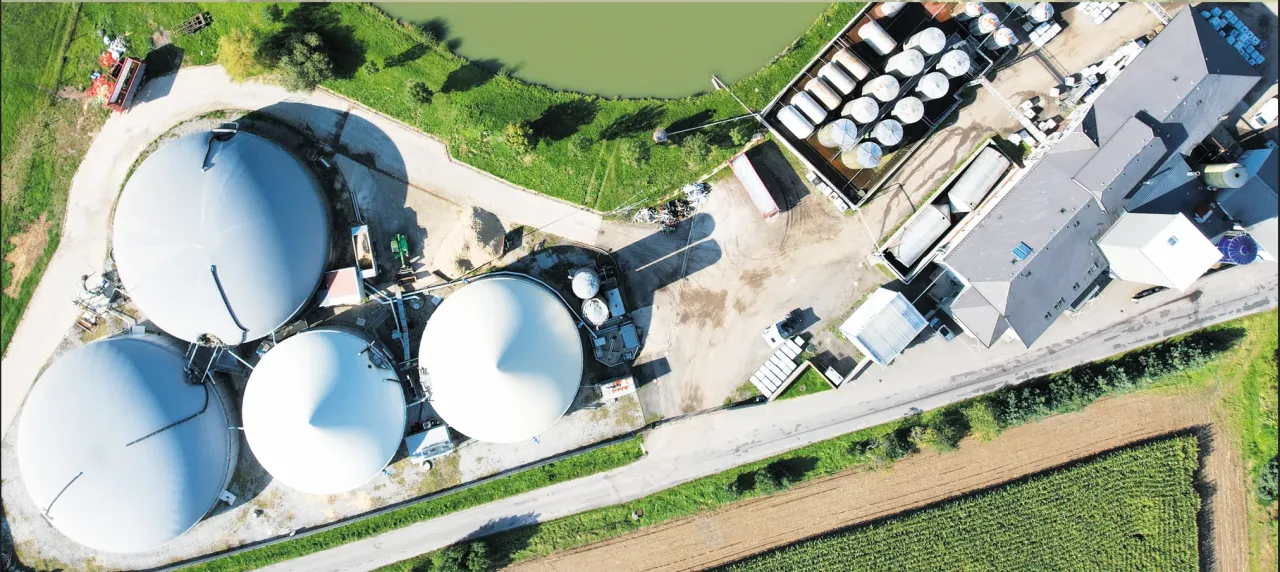 Rozw&oacute;j kogeneracji w oparciu o biogaz komunalny: widok z lotu ptaka na instalację z dużymi zbiornikami i budynkami gospodarczymi.