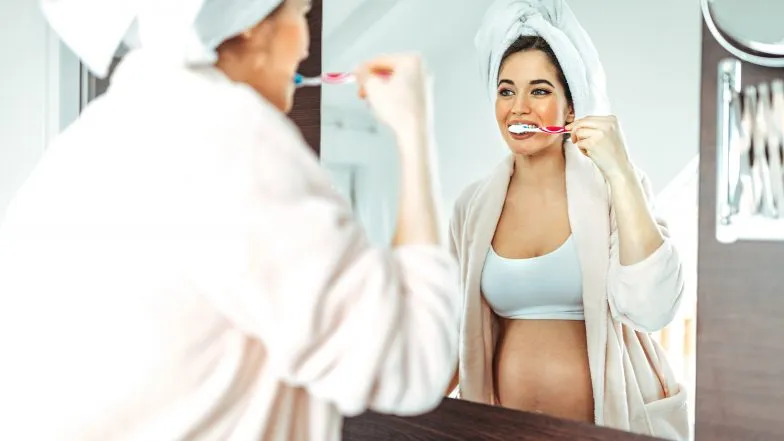 kobieta w ciąży myjąca zęby z uśmiechem