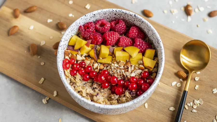 Miska owsianki z owocami i nasionami, z rozmytym tłem przedstawiającym zdrowe jelita lub schemat trawienia