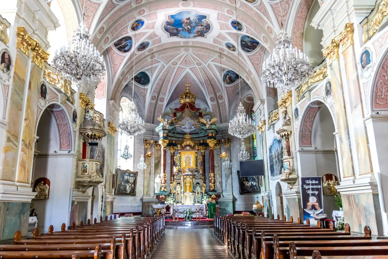 Wnętrze kościoła z ołtarzem i ławkami. Widać baner 