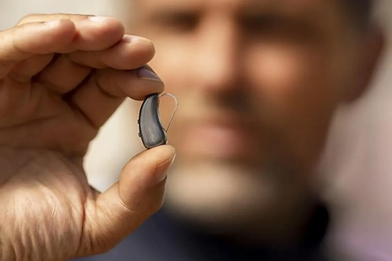 Dłoń trzyma dyskretny aparat słuchowy. Zastanawiasz się, ile kosztuje niewidoczny aparat słuchowy?