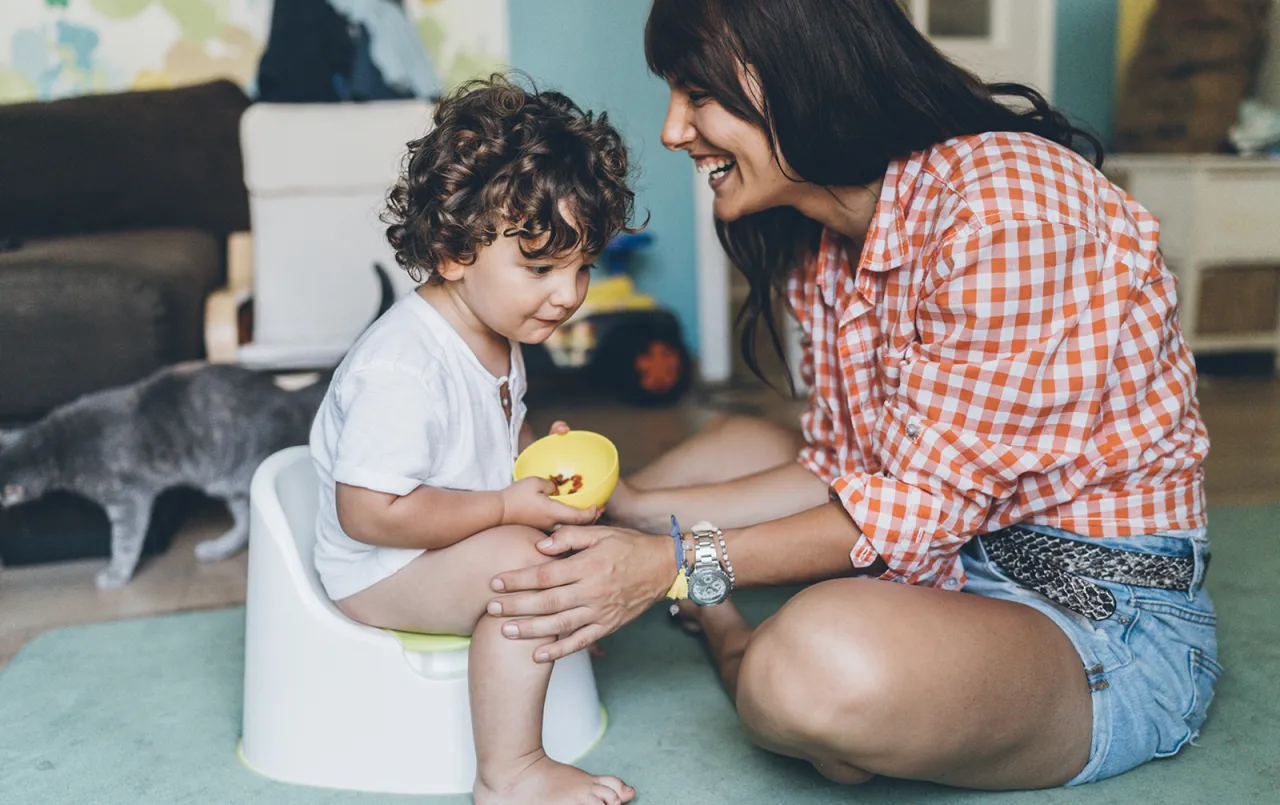 Rodzic z dzieckiem przy nocniku, uśmiechnięci, bez presji