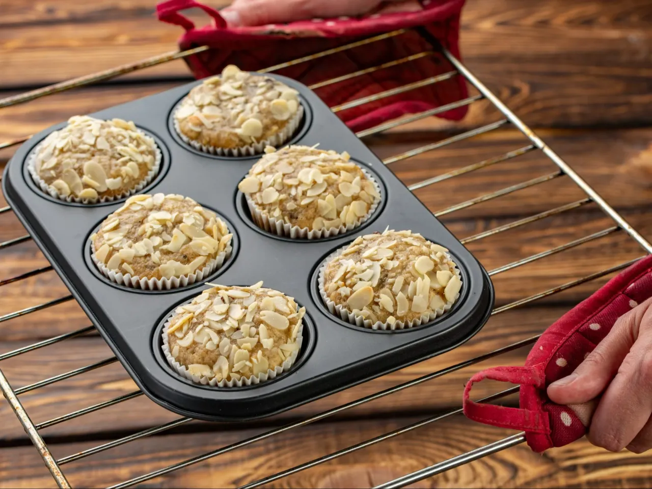 Sześć babeczek z płatkami migdał&oacute;w na wierzchu, gotowych do wyjęcia z piekarnika. Idealne na zdrowy przepis na babeczki.