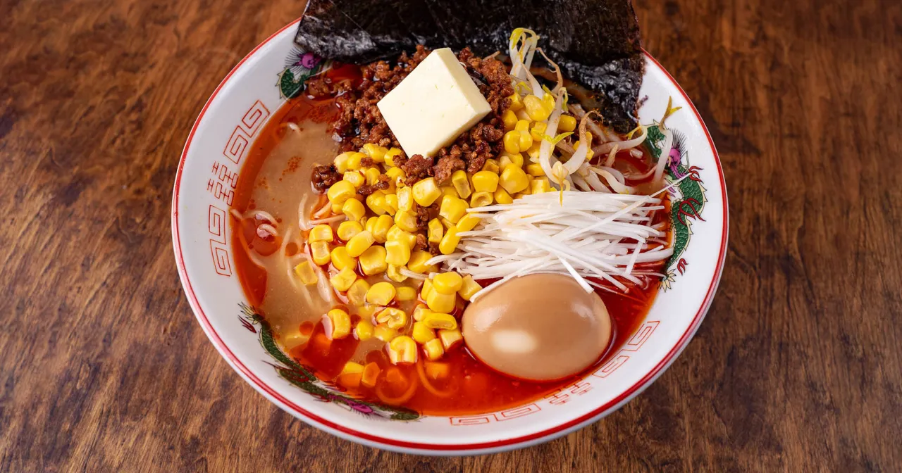 Miseczka ramenu z mielonym mięsem, kukurydzą, jajkiem i masłem. Pyszny, ale kaloryczny posiłek.