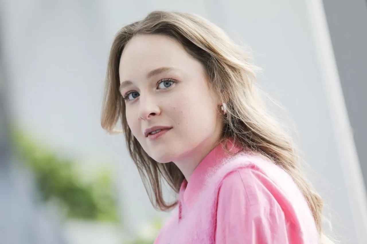 Maria Kowalska, aktorka, w różowej bluzce z puszystym kołnierzem, z niebieskimi oczami i blond włosami.