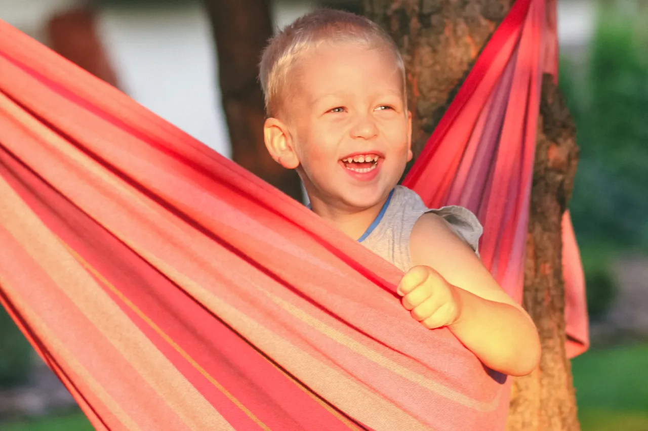 dziecko bawi się masą plastyczną, dziecko zawinięte w koc, dziecko huśta się na hamaku