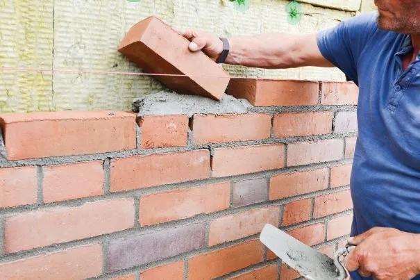 osoba stawiająca mur z cegieł jako metafora granic