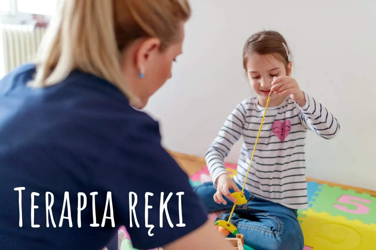 Terapia ręki ćwiczenia: dziewczynka z terapeutką bawią się zabawką rozwijającą motorykę małą.