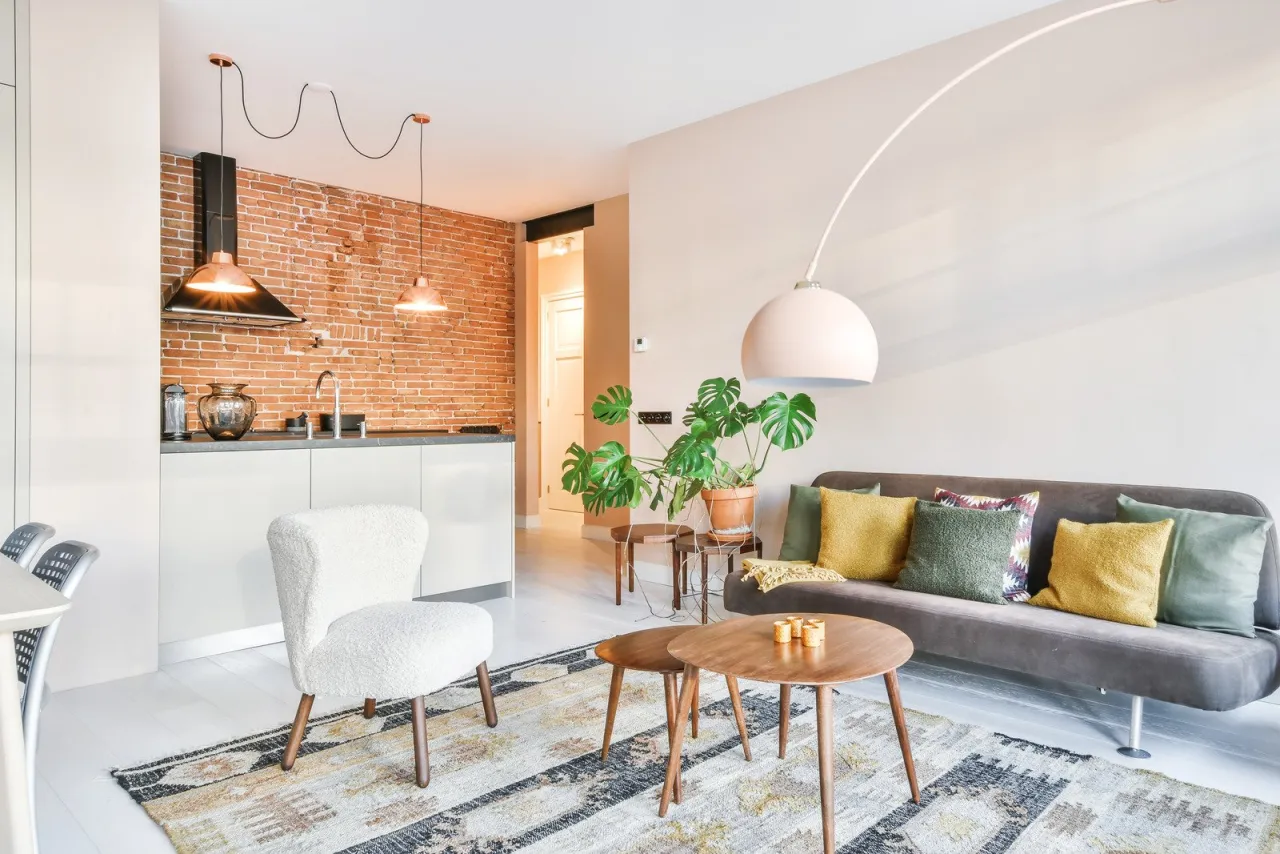 Stylowa aranżacja małego mieszkania: kuchnia z ceglaną ścianą, przytulny salon z sofą i roślinami.