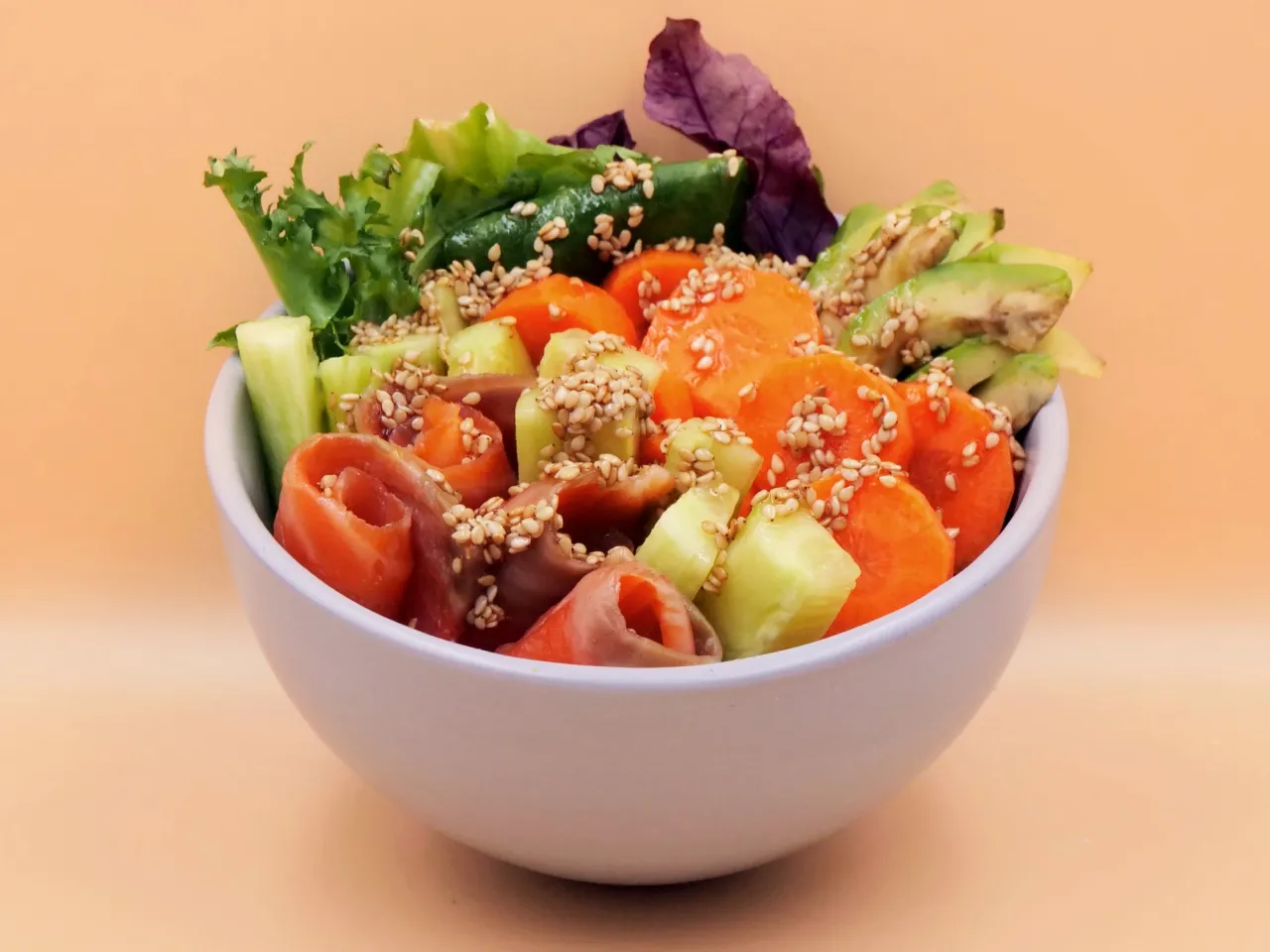 Miseczka sushi z łososiem, awokado, og&oacute;rkiem, marchewką i sezamem.