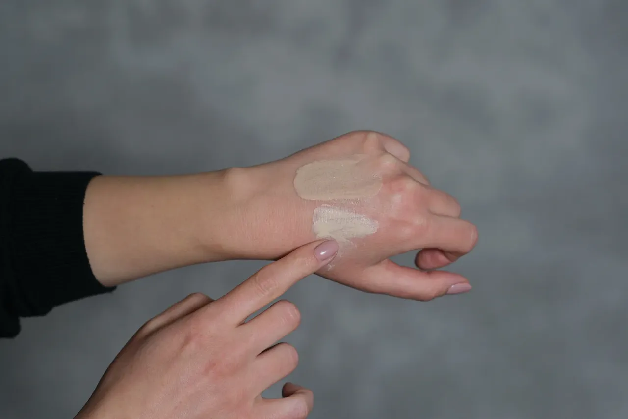 Kobieta testująca podkład na sk&oacute;rze, r&oacute;żne odcienie podkładu