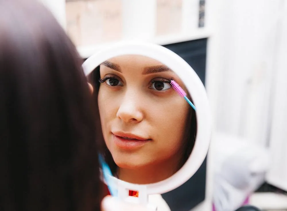 kobieta nakładająca odżywkę na rzęsy