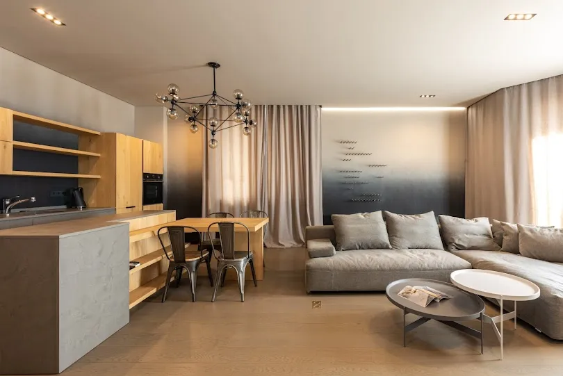 Salon z aneksem kuchennym wydzielony stołem i wyspą