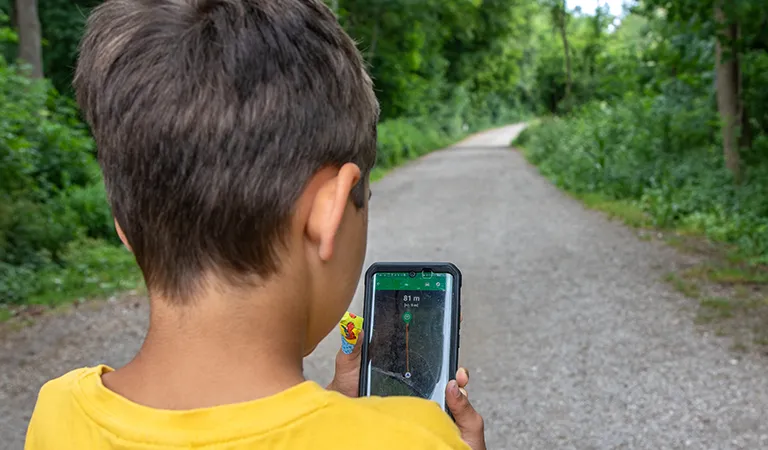 Familie beim Geocaching im Wald mit Smartphone