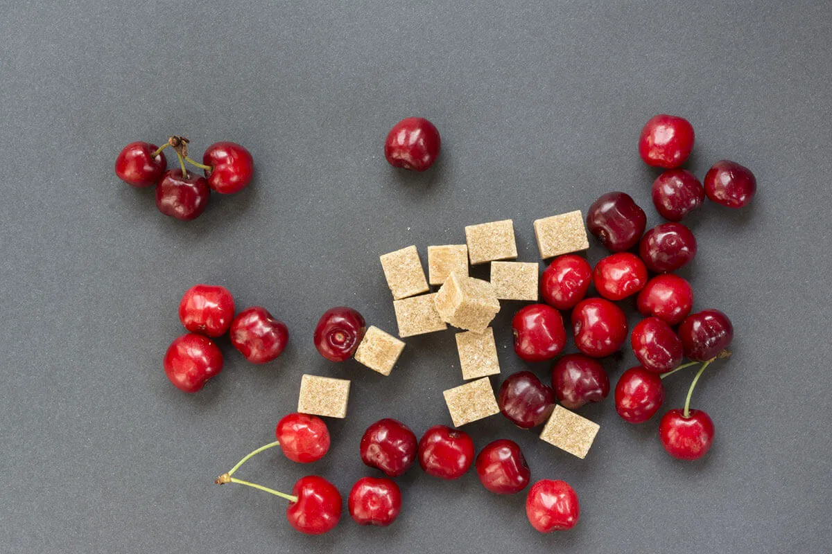Kostki cukru obok miski zupy owocowej, symbolizujące zawartość cukru