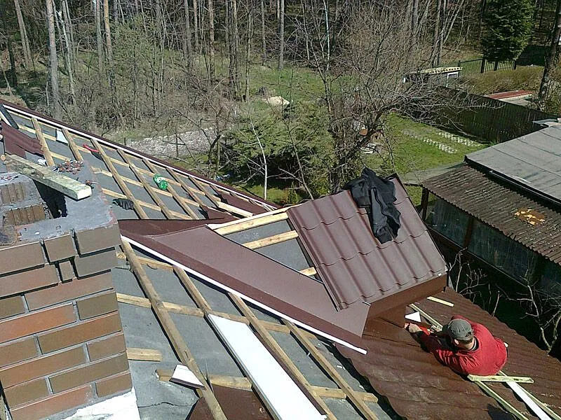 Dekarz na dachu montujący pokrycie lub wykonujący obr&oacute;bki blacharskie