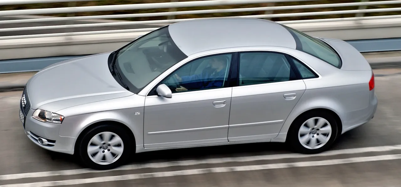 Srebrny sedan w ruchu, idealny dla szukających najbardziej ekonomiczne auto. Kierowca w niebieskiej kurtce.