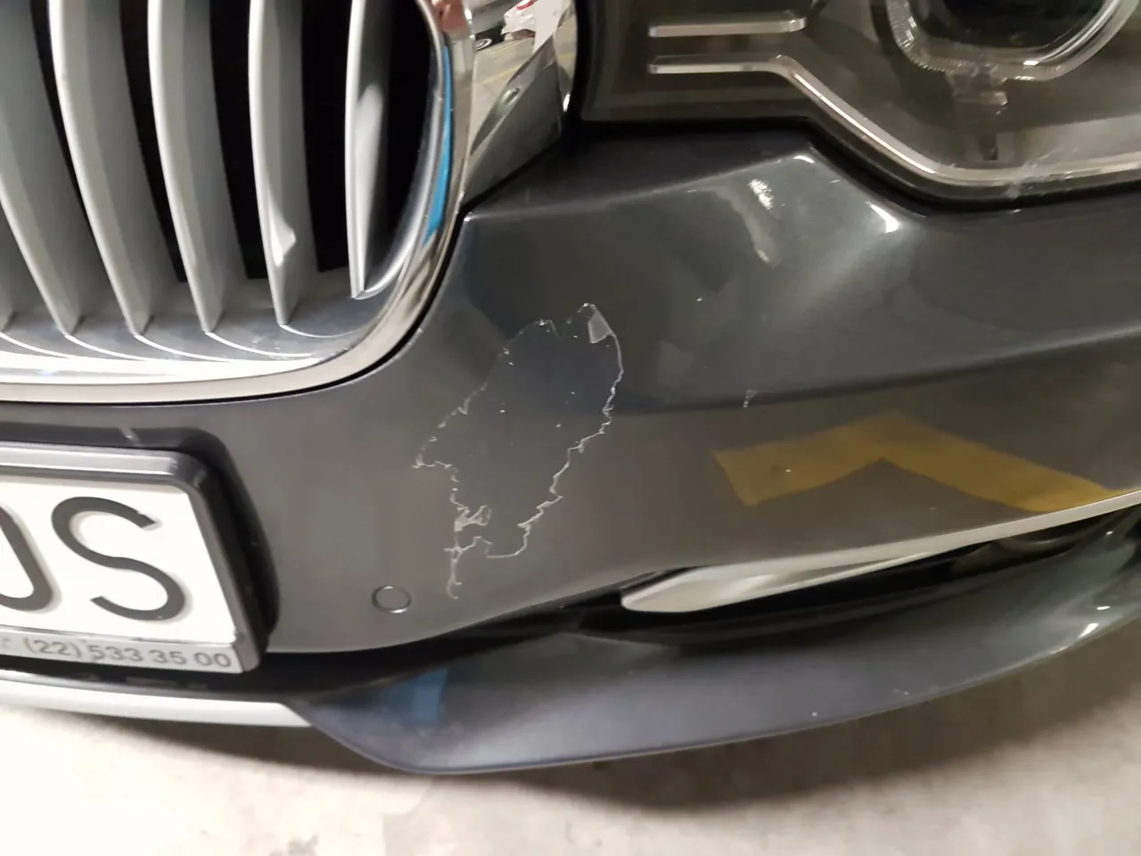 Uszkodzony zderzak w kolorze, z odpryskami lakieru, wymaga malowania. Widać różnicę między zderzakiem w kolorze a zderzakiem do malowania.