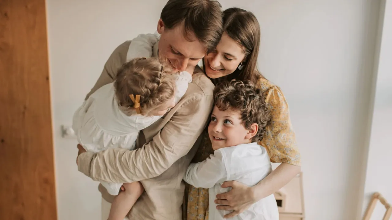 Rodzina w uścisku. Widać, co daje przytulanie: radość, bliskość i miłość między rodzicami i dziećmi.