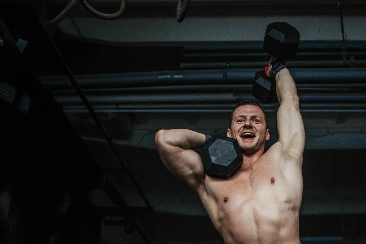 Uśmiechnięty mężczyzna podnosi ciężary. To dow&oacute;d, jak crossfit zmienił moje życie, dając siłę i radość.