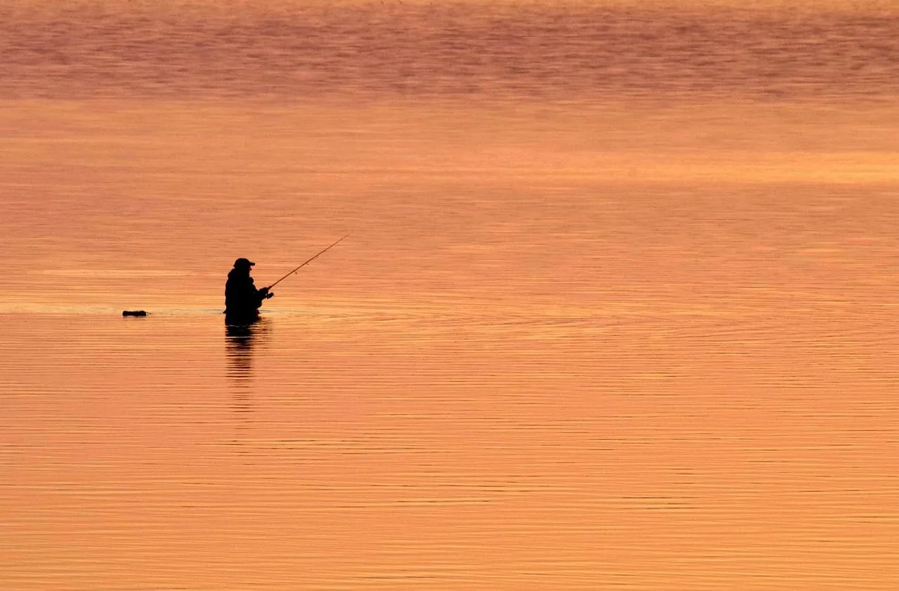 Sylwetka wędkarza w wodzie o zachodzie słońca. Idealne miejsce, by dowiedzieć się, na co łowić ryby w Chorwacji.