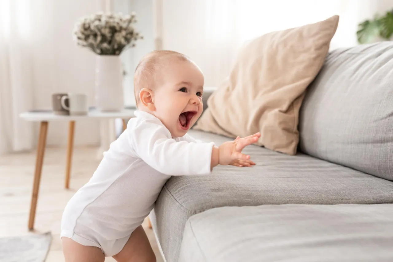 dziecko raczkujące i wstające przy meblach