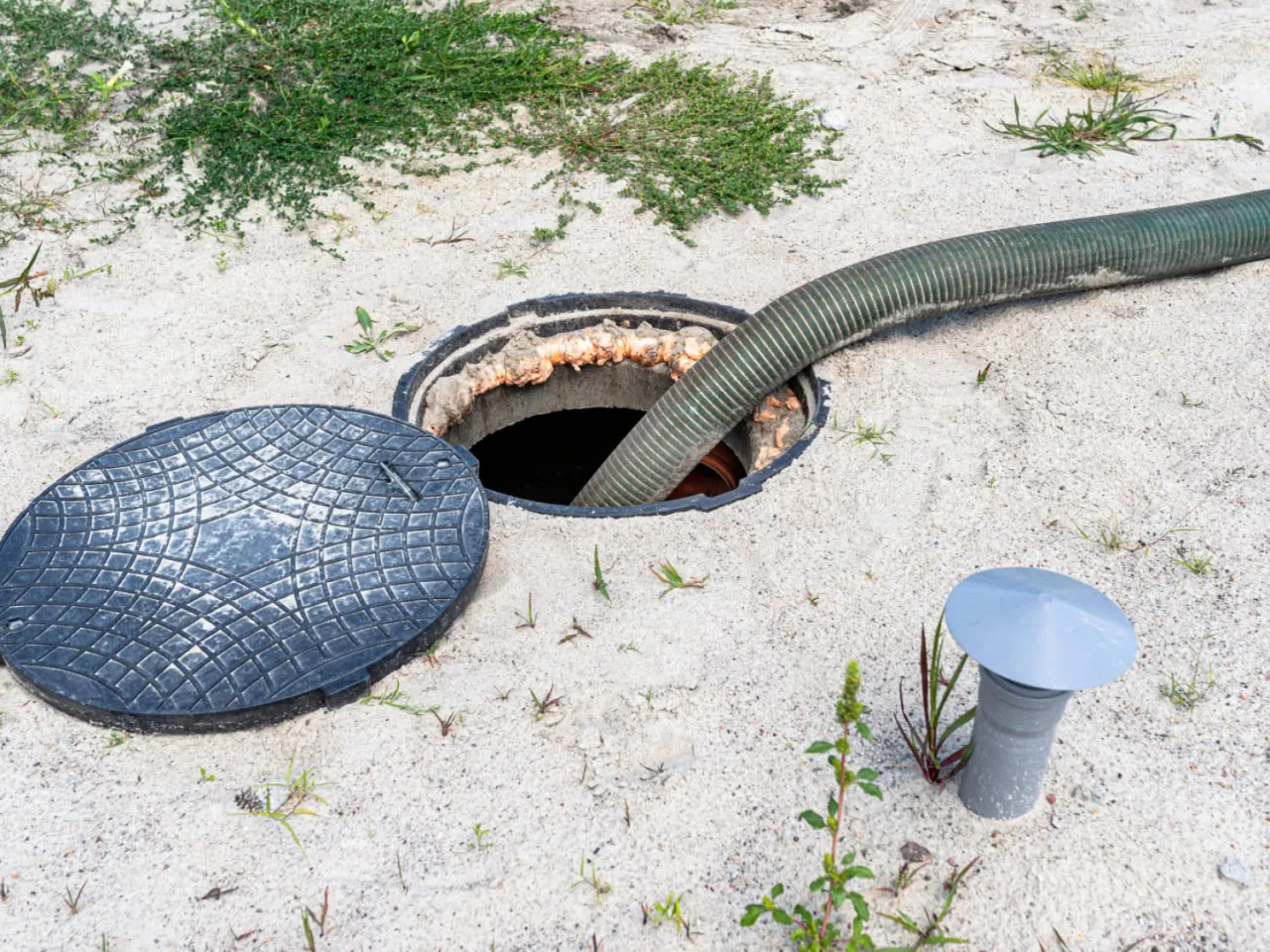 Odkryta studzienka kanalizacyjna z wężem, obok odpowietrznik. Może to być pow&oacute;d, dlaczego śmierdzi z oczyszczalni biologicznej.