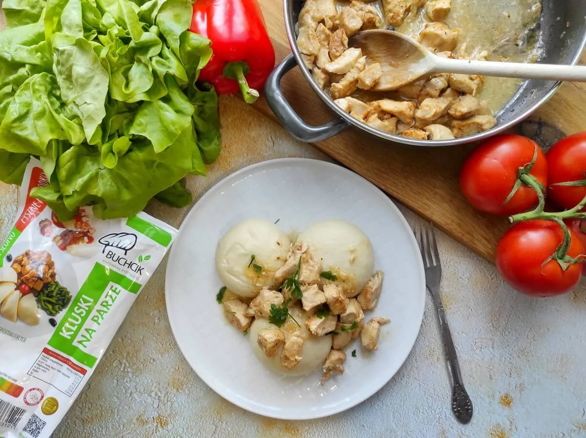 Kluski na parze z kurczakiem i sosem. Idealny pomysł na to, co można ugotować na parze. Obok sałata, papryka i pomidory.