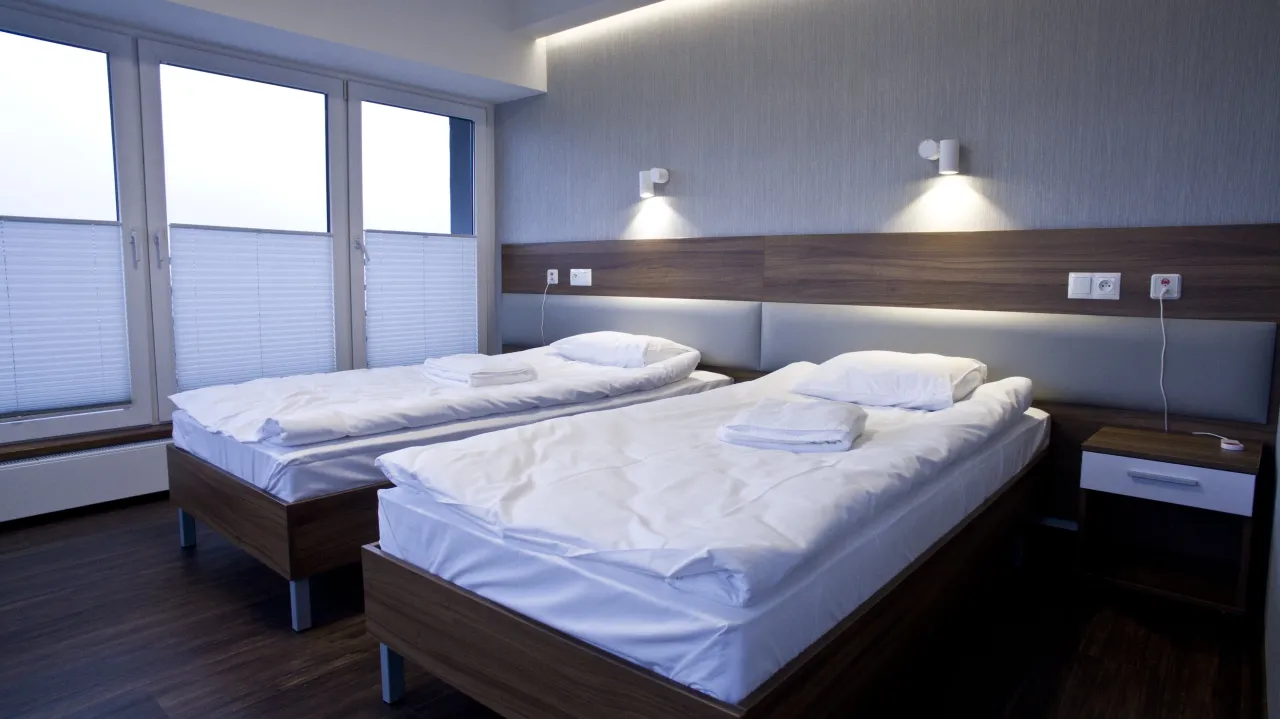 Pokój w sanatorium z dwoma łóżkami, idealny dla pary lub przyjaciół. Zastanawiasz się, jaki wybrać pokój w sanatorium? Ten z widokiem na okno i wygodnymi łóżkami to dobry wybór.