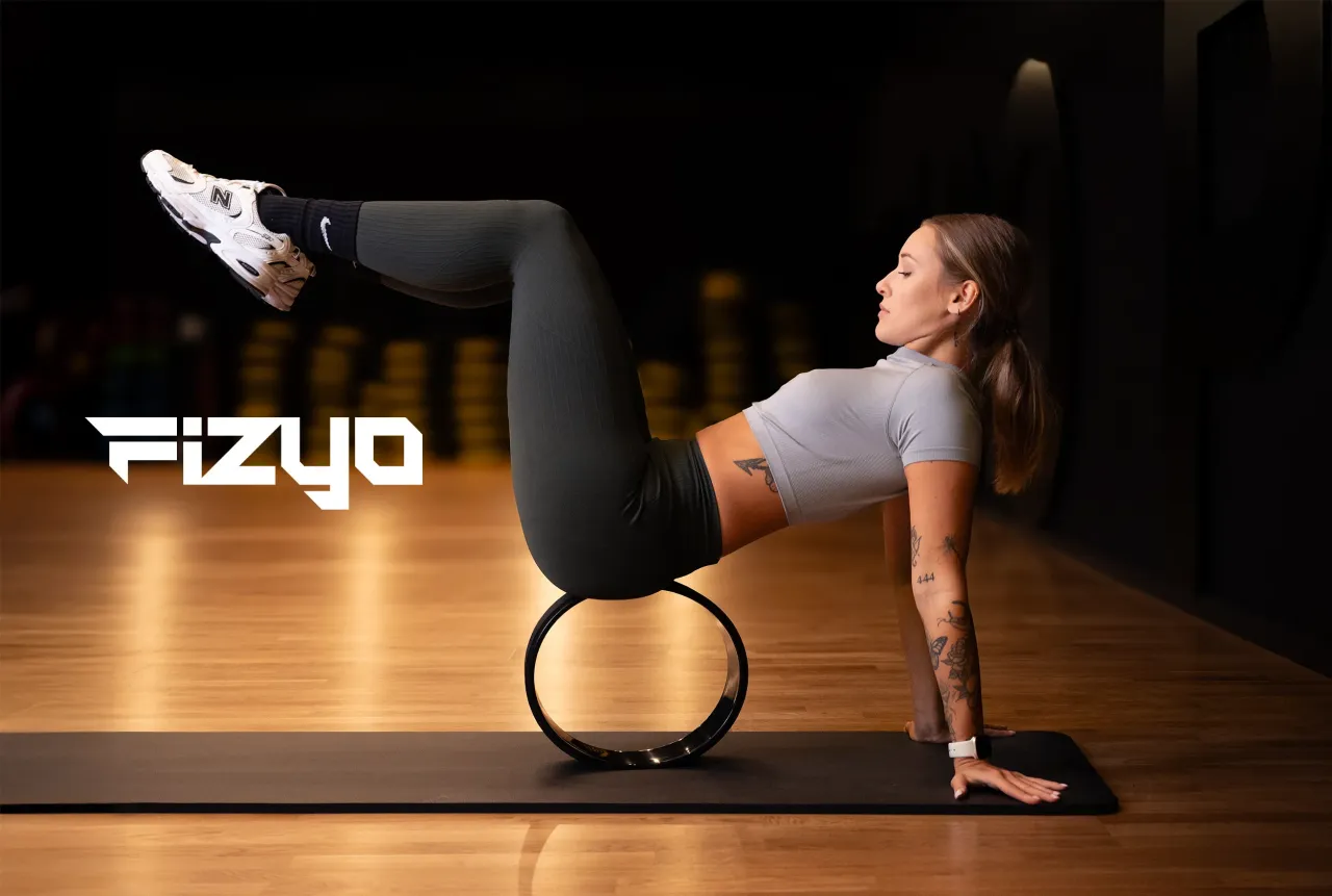 Kobieta ćwiczy z kołem do pilatesu, pogłębiając wiedzę, co lepsze na kręgosłup joga czy pilates.