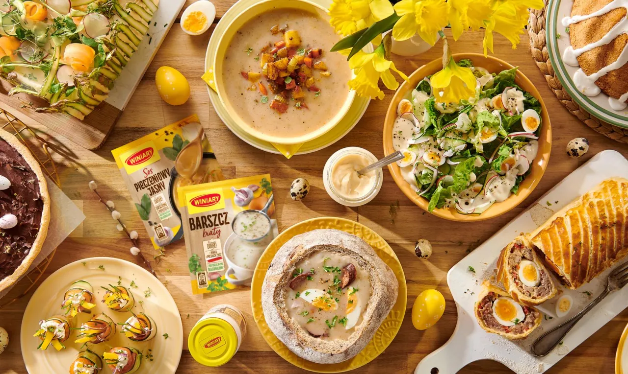 Co ugotować na Święta Wielkanocne? Na stole pyszne potrawy: żurek, sałatka, pieczeń, ciasto i przekąski.