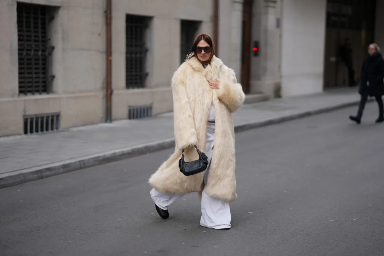 Kremowe, długie sztuczne futro i białe spodnie tworzą stylowy look. Czy sztuczne futra są modne? Ta stylizacja udowadnia, że tak!